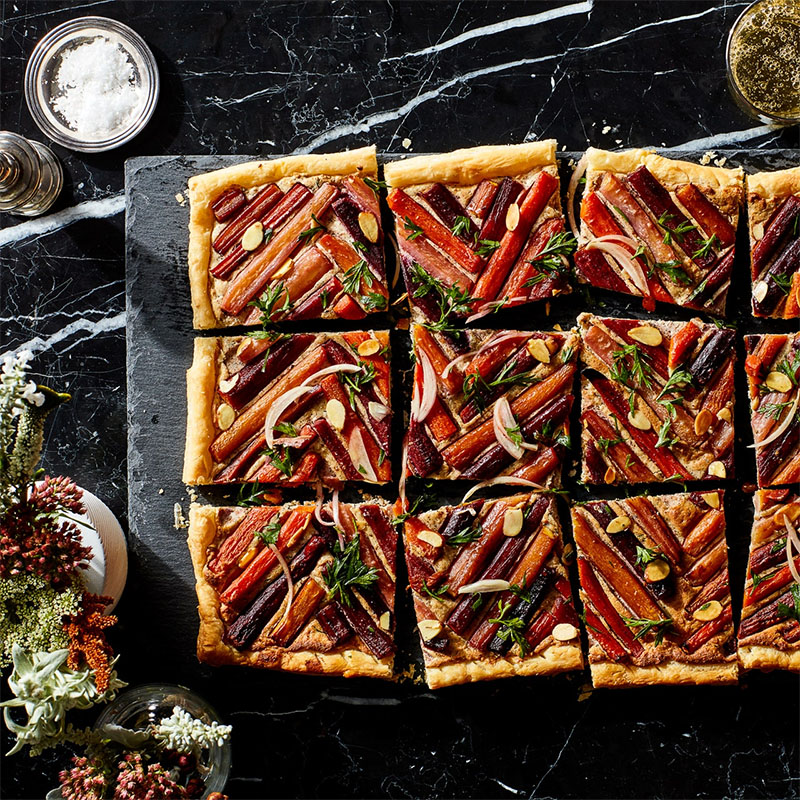  Arranging the carrots in a geometric pattern transforms this savory tart into a truly show-stopping appetizer, while a zesty carrot top garnish provides a nice pop of color and flavor.